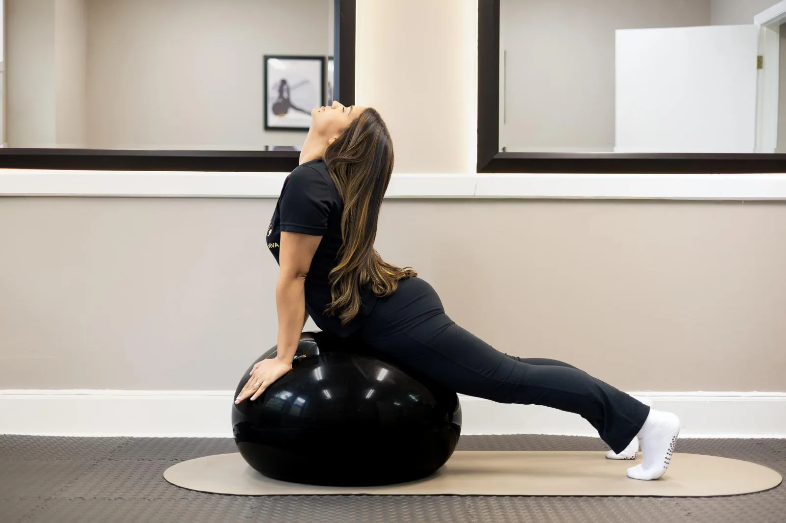 Estiramiento de extensión de espalda sobre una pelota de ejercicio en un mat de Pilates