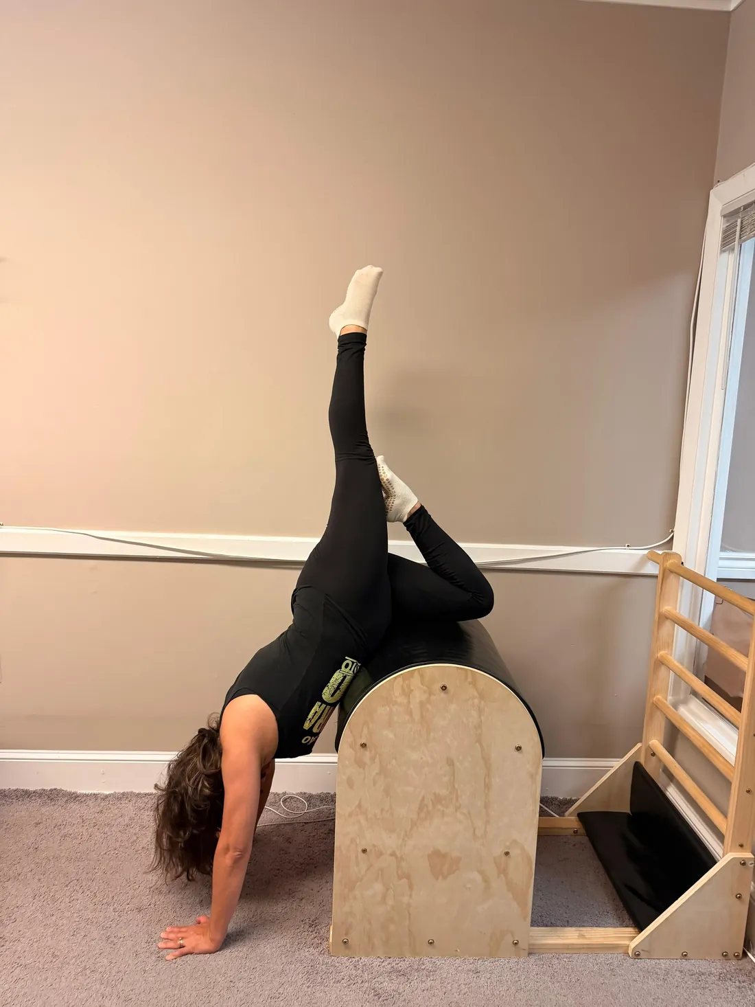 Client in a supported stretch on the Ladder Barrel at a Pilates studio in Lowell