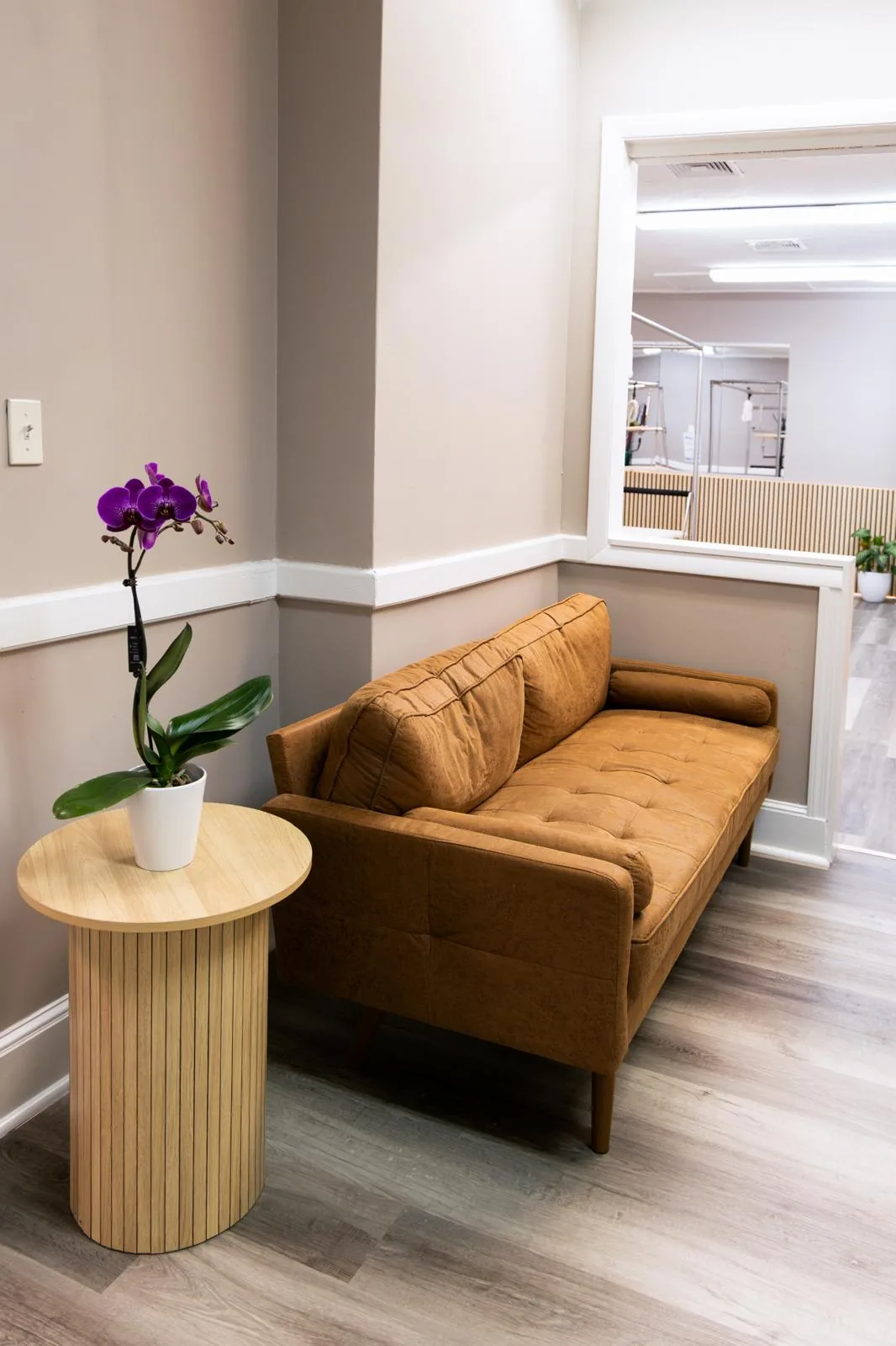 Sala de espera aconchegante com sofá de couro e uma orquídea no Inspire Pilates Studio
